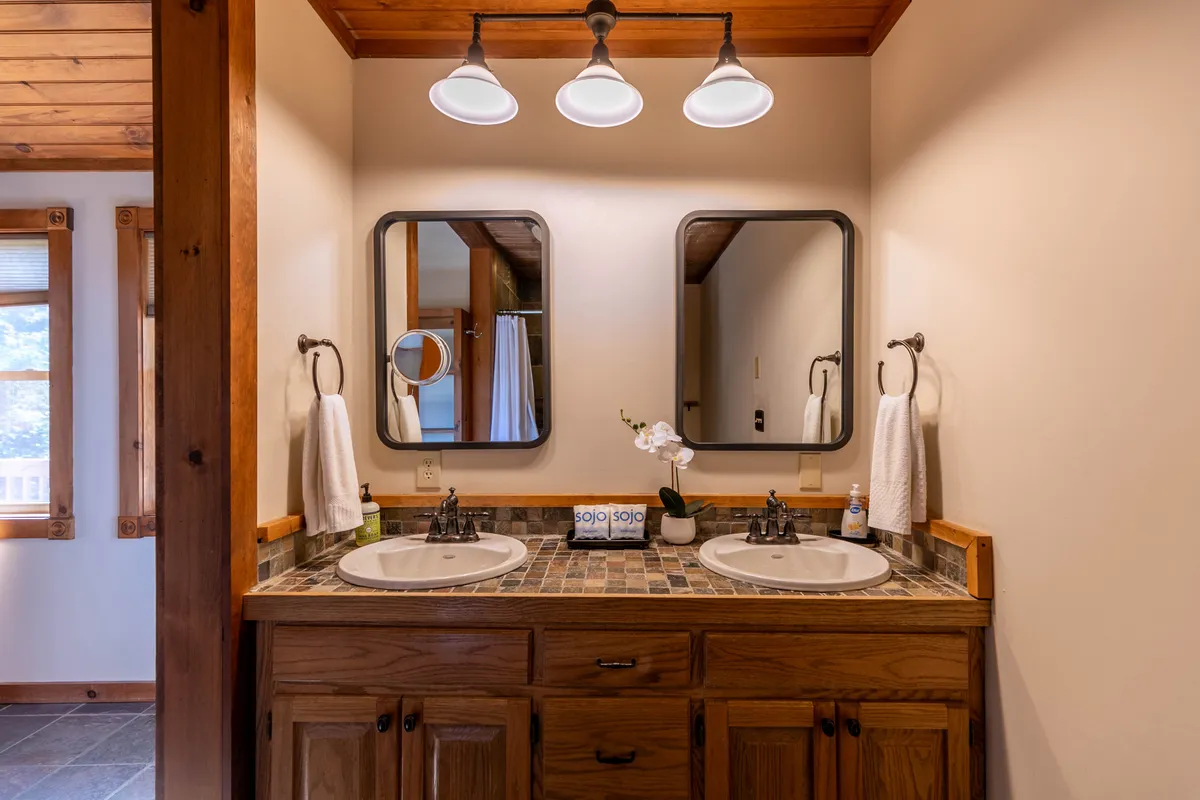 A stylish bathroom with double sinks, elegant mirrors, decorative tile, and soft lighting, creating a spa-like environment ideal for morning or evening routines.