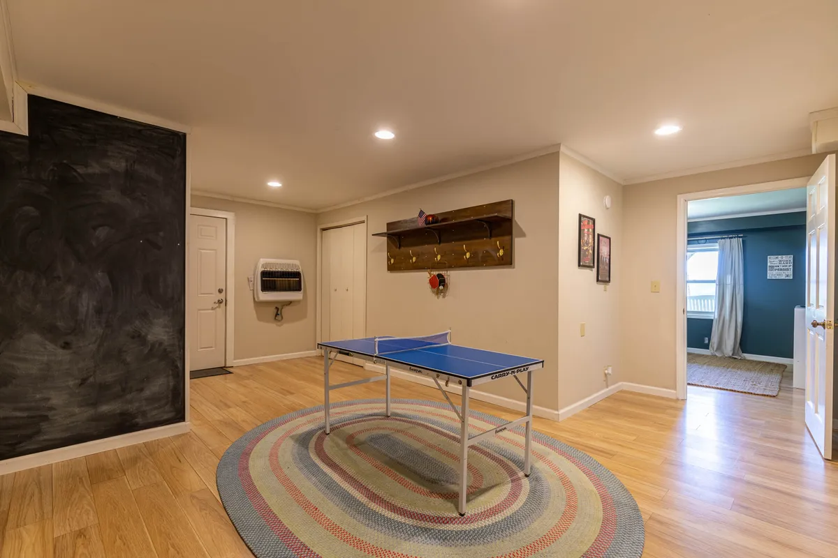 An indoor game area featuring a ping pong table, a chalkboard wall, and a doorway leading further into the home. The space is designed for playful competition and casual hangouts, providing a vibrant setting for friend groups to enjoy memorable game nights together.